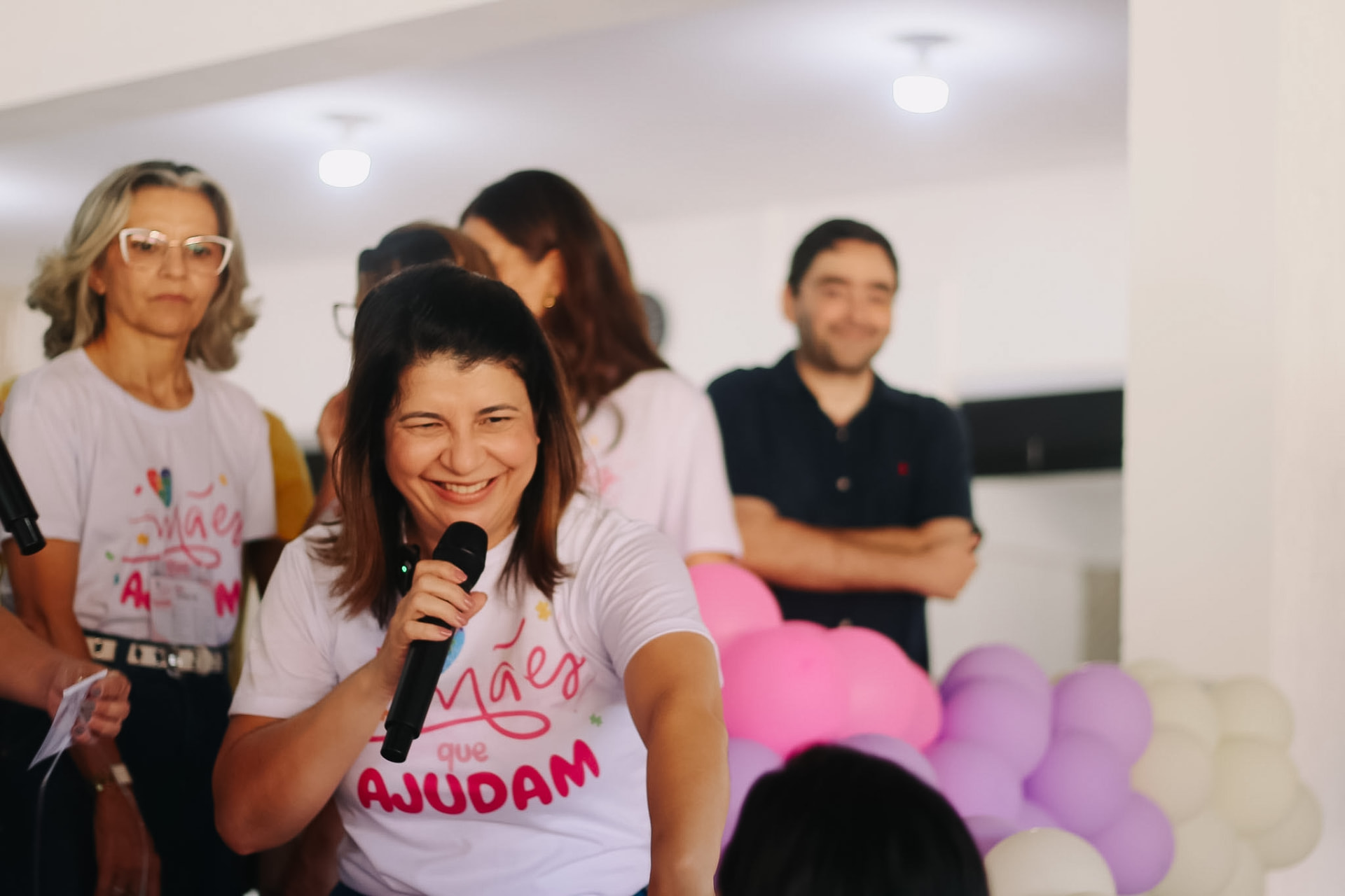 Carla Dickson falando ao microfone em encontro do projeto Mães que Ajudam